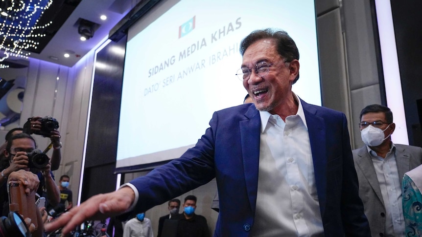 Malaysia's opposition leader Anwar Ibrahim smiles and gestures as he leaves a press conference.
