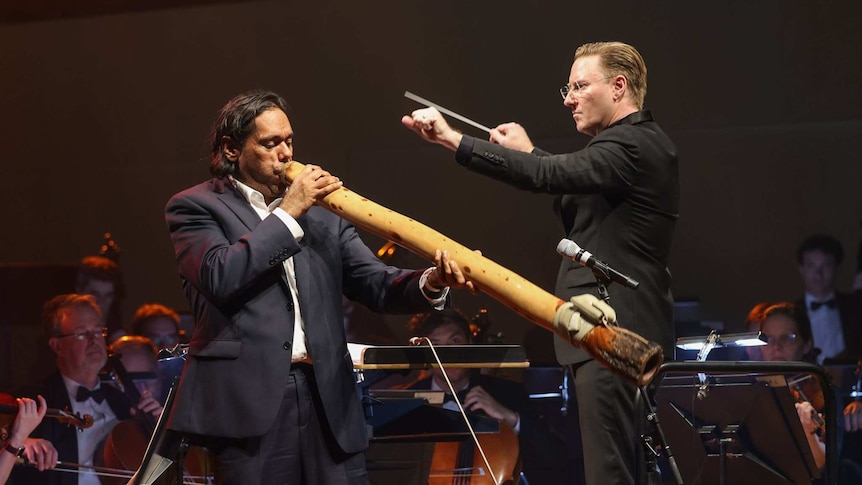 William Barton playing didgeridoo in front of the Queensland Symphony Orchestra, with Benjamin Northey conducting