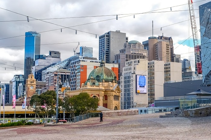 A photo overlooking Flinders Street Station from across Federation Square, on a slightly cloudy day.