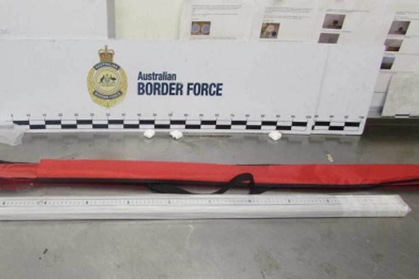 A long ruler sits on the ground in front of a cover and Australian Border Force signage.