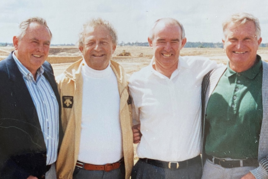 Four men stand outside and pose for a photo before planting trees.