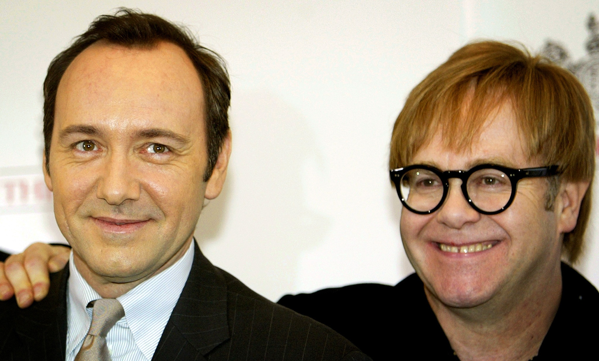 Elton John places an arm around Kevin Spacey 