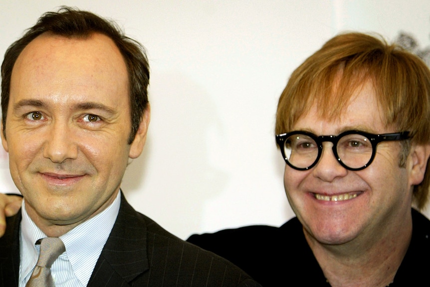 Elton John places an arm around Kevin Spacey 