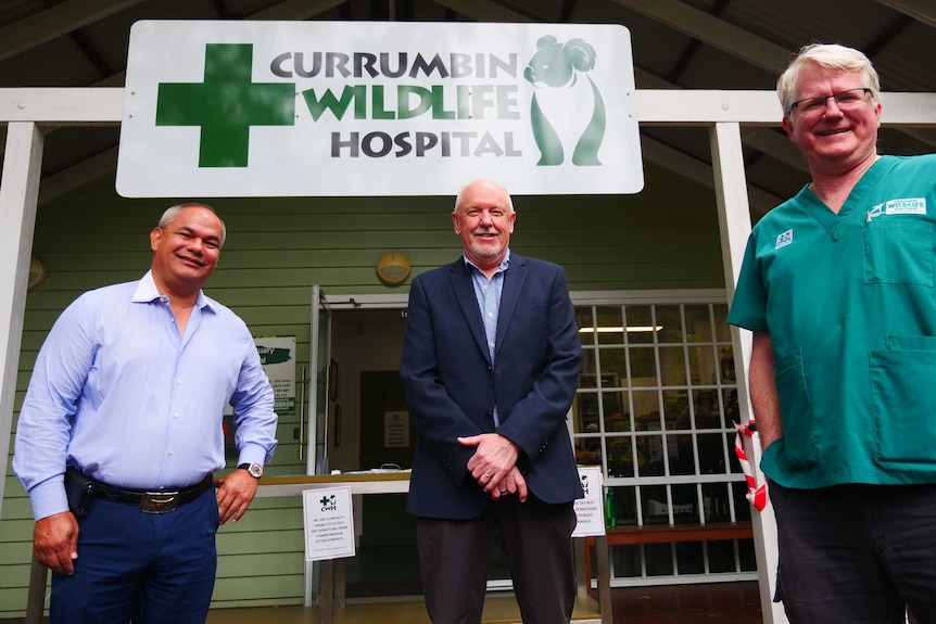 three men standing standing in front of a building with a Currumbin Wildlife hospital sign