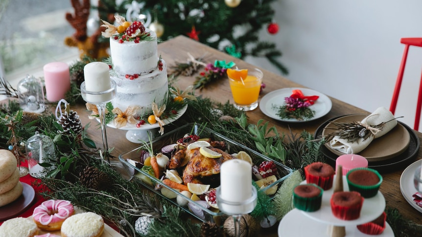 Table set with lavish food and cake with a Christmas tree in the background