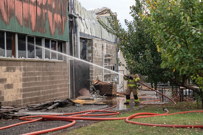 A firefighter trains water on a building