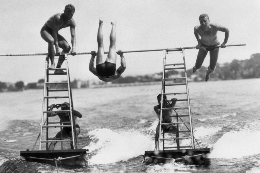 Acrobats perform a stunt on ladders over water