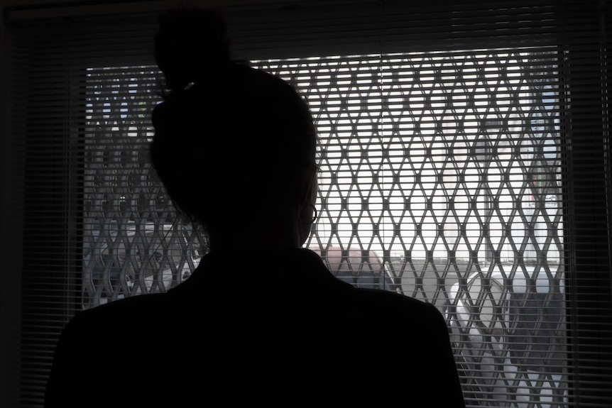 A silhouette of a woman as she looks out of a window