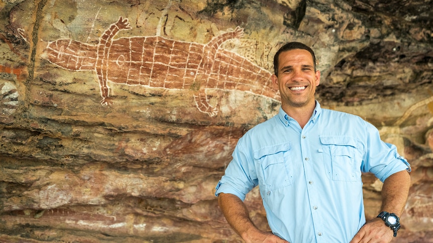 Phil Breslin stands in front of Indigenous rock art