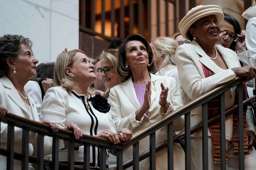 A group of women standing together while wearing white.