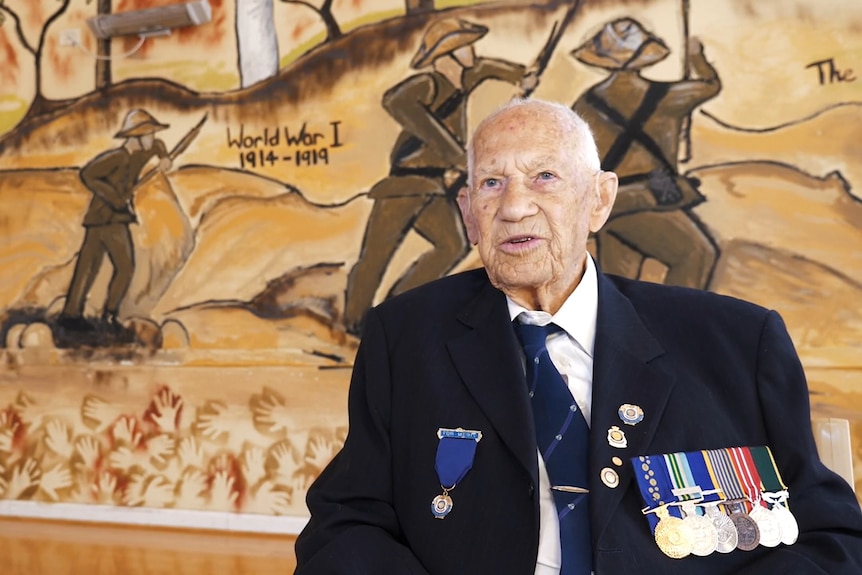An older gentleman in a blue suit, wearing war medals.
