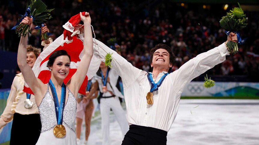 Tessa Virtue (L) and Scott Moir hold a Canadian flag after winning gold in ice dance at Vancouver.