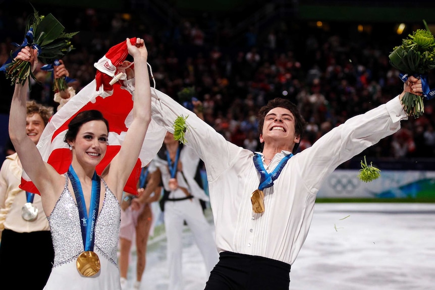 Tessa Virtue (L) and Scott Moir hold a Canadian flag after winning gold in ice dance at Vancouver.
