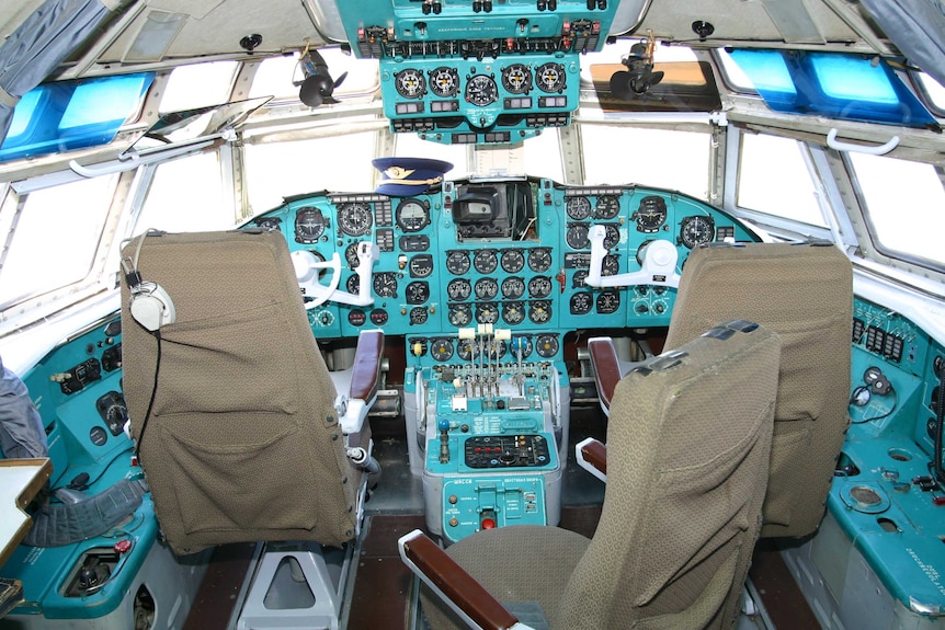 A wide view shows the cockpit and controls of a Ilyushin Il-62 plane.