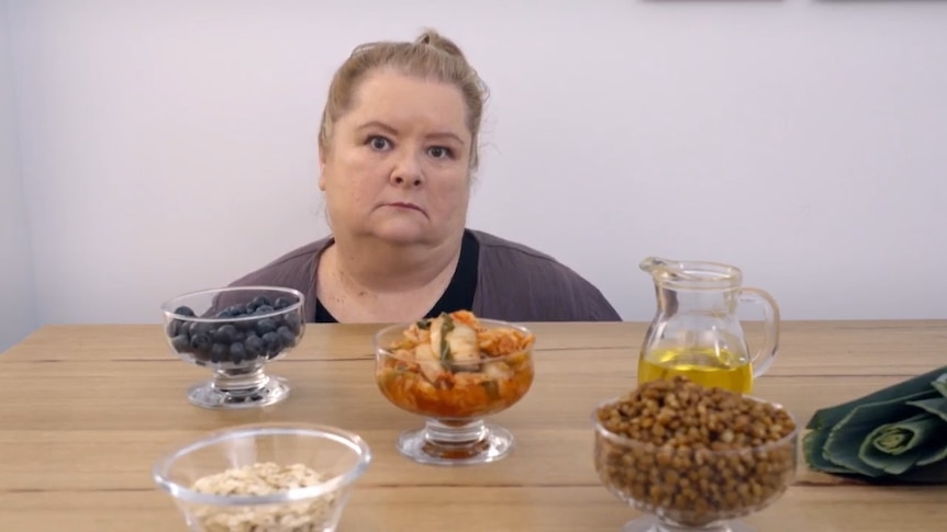 Magda Szubanski looks unhappy while sitting in front of bowls of different foods