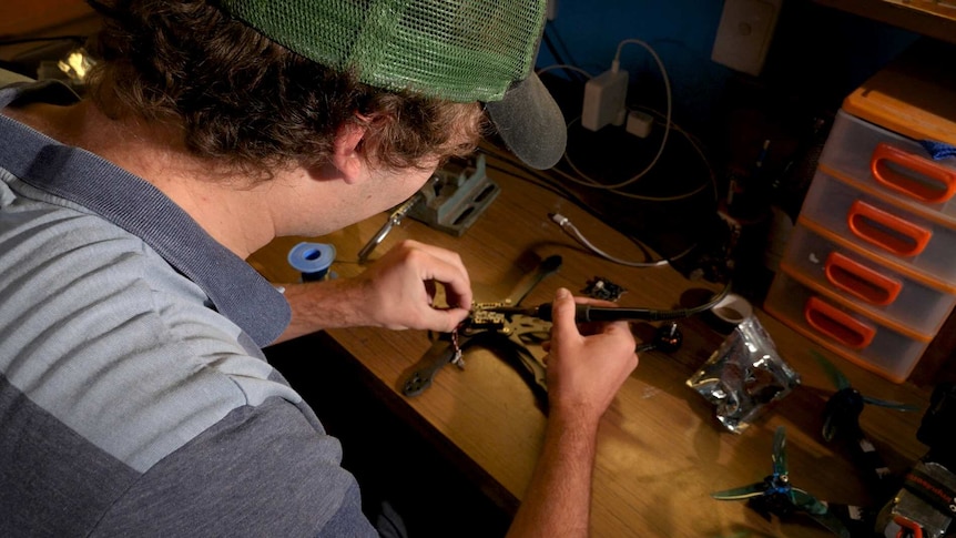 A young man solders pieces together to build a drone.
