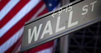 Wall Street sign in front of blurred American flag.