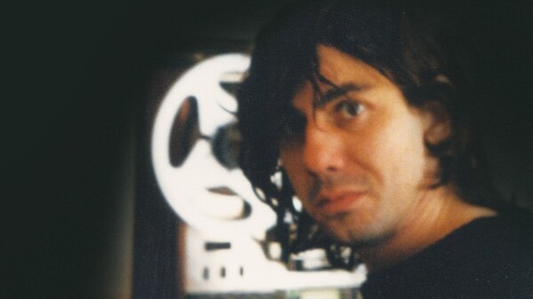 Candid photo of a man with longish hair standing in front of a eight track tape machine