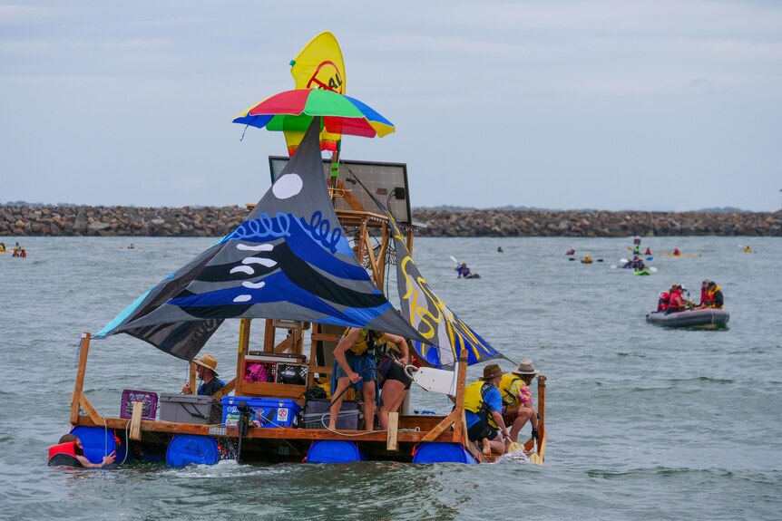 A float made of blue barrels and bamboo with flags on the water in a shipping channel.