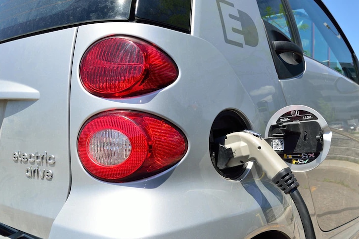 A close-up photo of an electric vehicle charging at a port. 