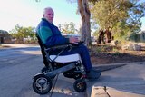A man in a wheelchair tries to navigate a curb.