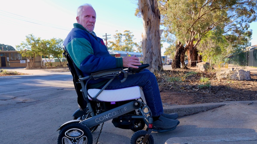 A man in a wheelchair tries to navigate a curb.