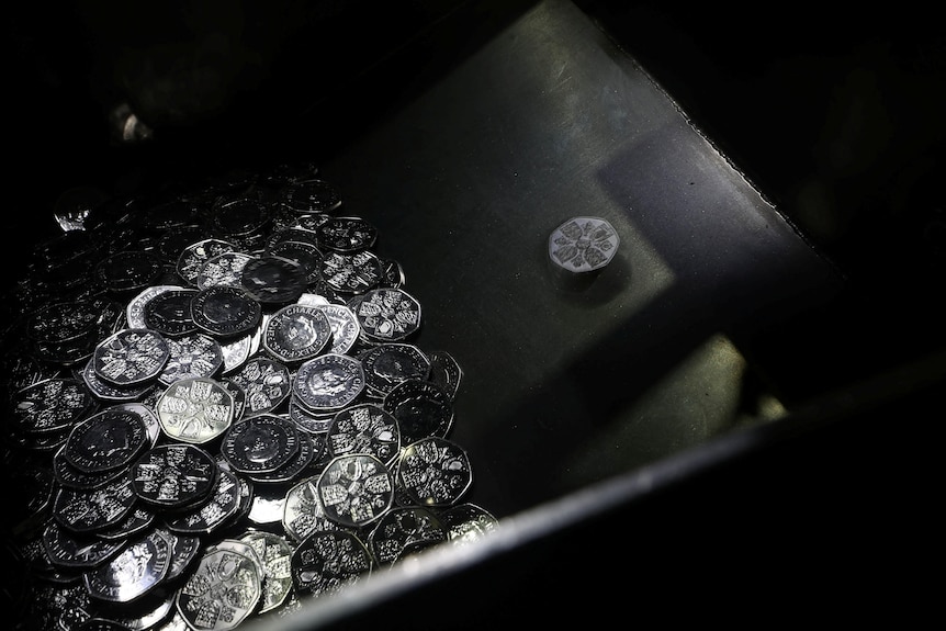 A pile of coins at the bottle of a metal container