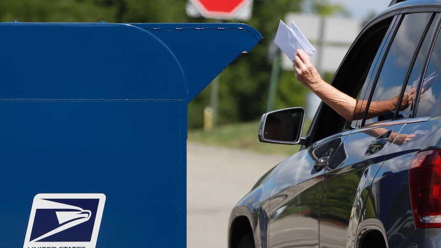 A driver puts mail in a US Post Office box.