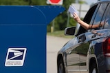 A driver puts mail in a US Post Office box.
