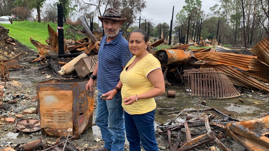 Lorena Granados and Gaspar Roman standing amid the burnt out and rusted wreckage of their shop