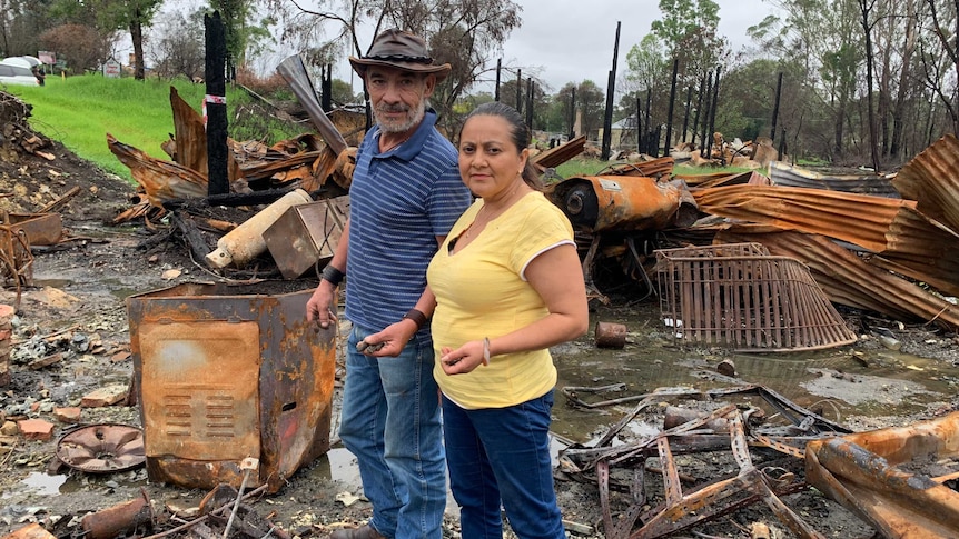 Lorena Granados and Gaspar Roman standing amid the burnt out and rusted wreckage of their shop