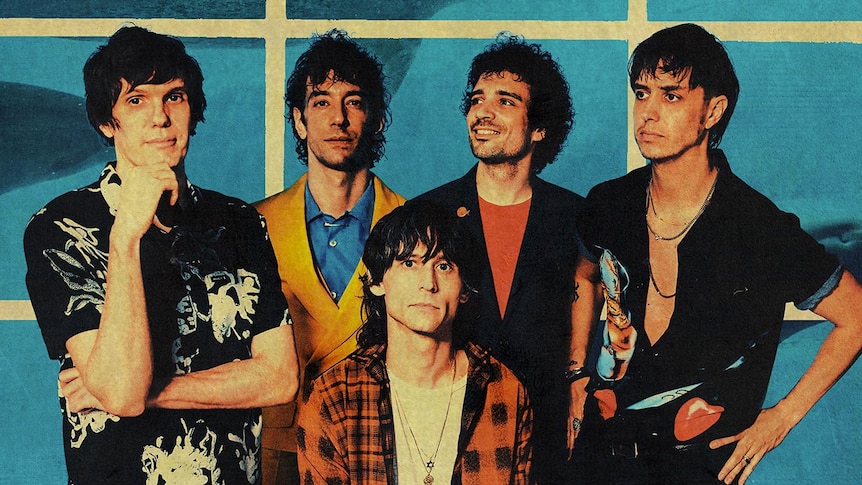 Five members of The Strokes stand in front of a blue and white wall