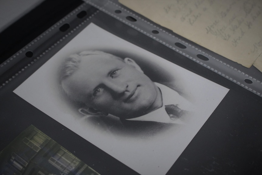 A image of a black and white photo of man sitting on a table.