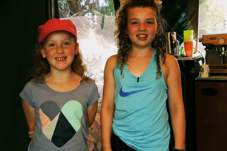 Two girls (cousins) standing in tent smiling