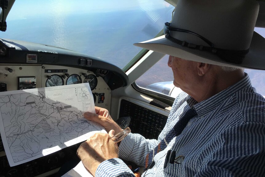 Bob Katter looks at a map while sitting in a small plane.