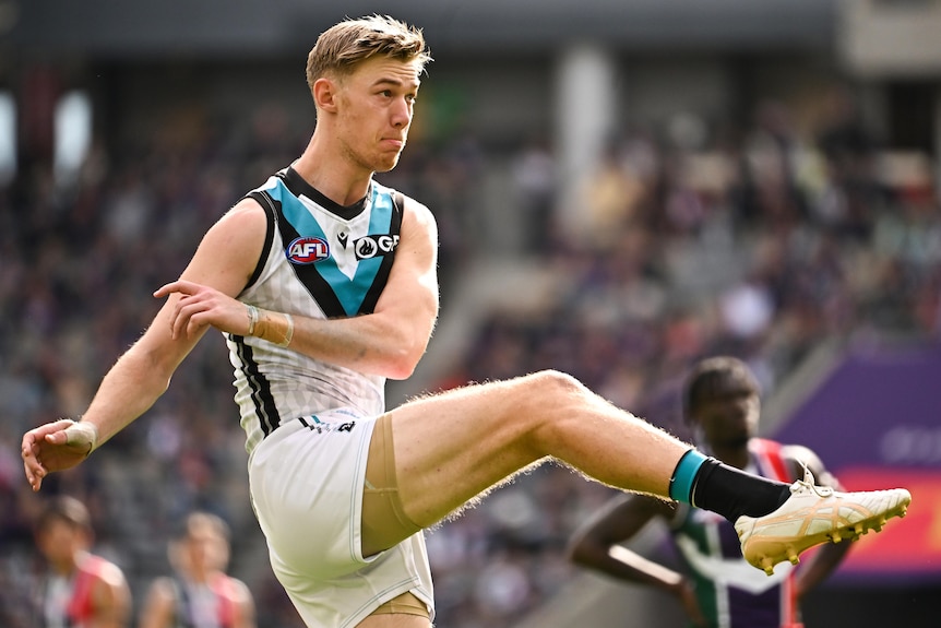 A Port Adelaide player performing a kicking motion during an AFL match.