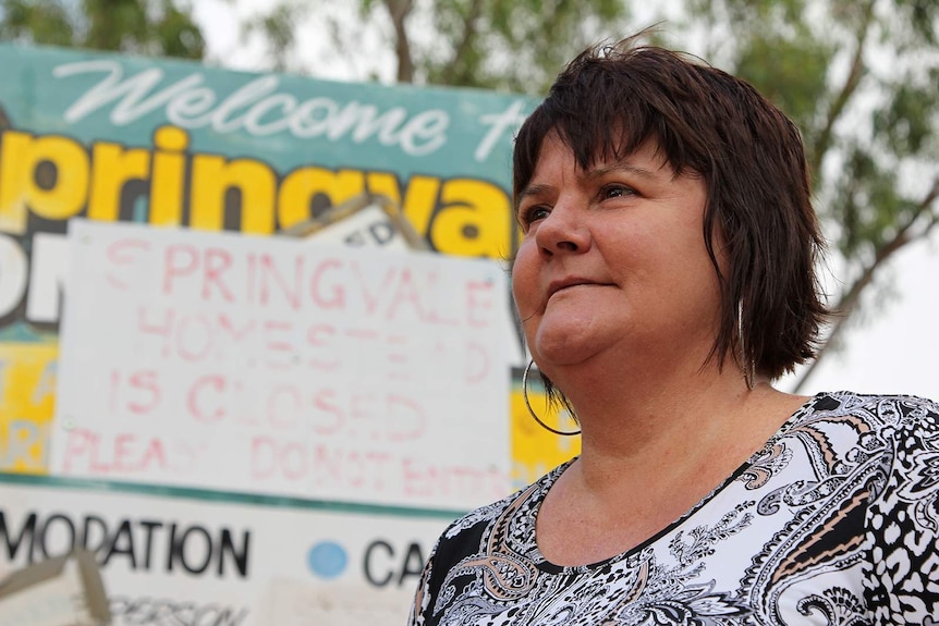 A photo of Kylie Chambers with a 'Springvale Homestead is Closed' sign behind her.