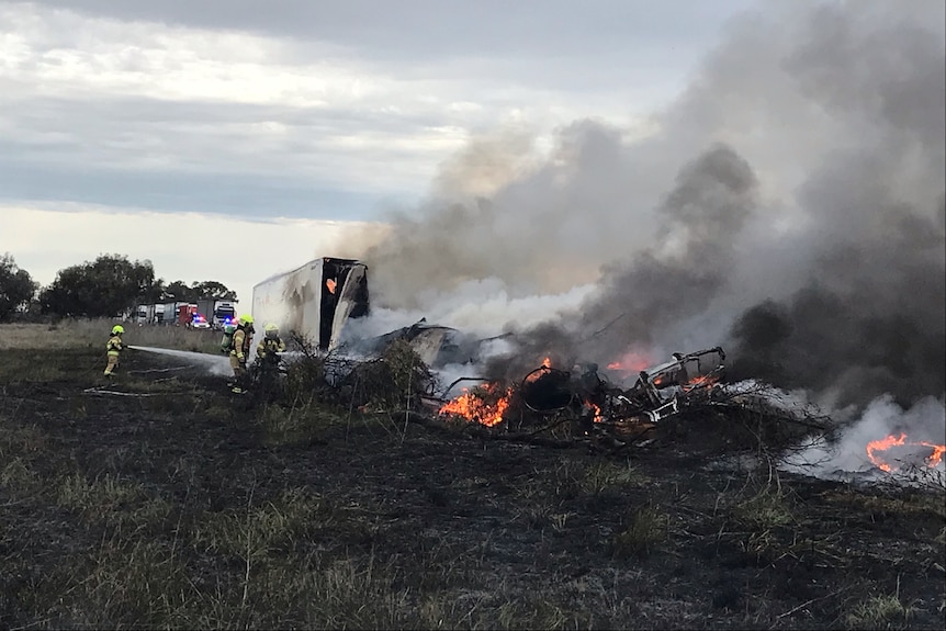 Firefighters extinguishing a truck fire on the side of the road.