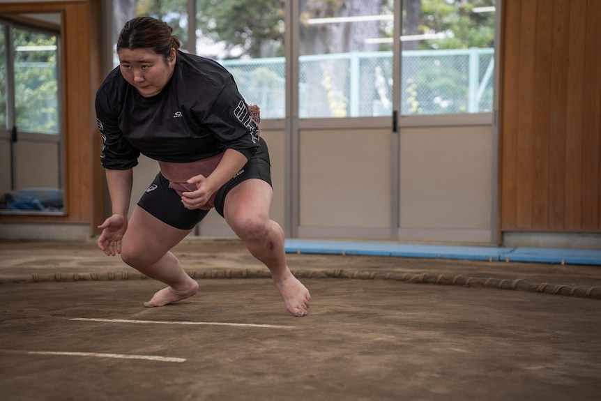 A woman races into a sumo ring 