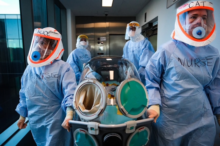 Medical staff in hazmat suits carry patient in a clear container