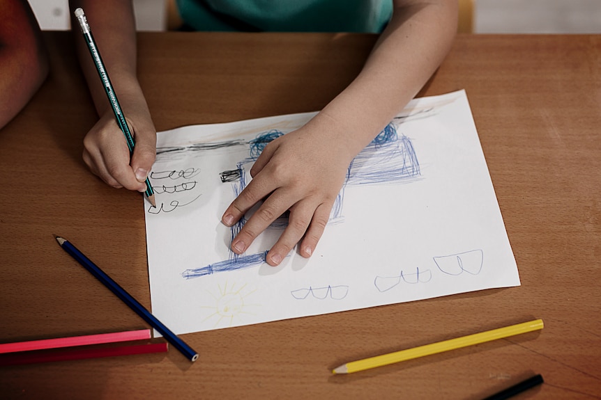 The hands of a child drawing with coloured pencils