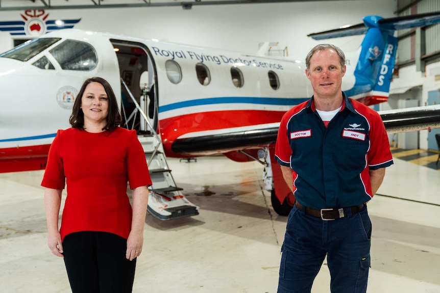 RFDS chief executive Rebecca Tomkinson and doctor Andy Hooper stand posing for a photo in front of a plane in a hanger.