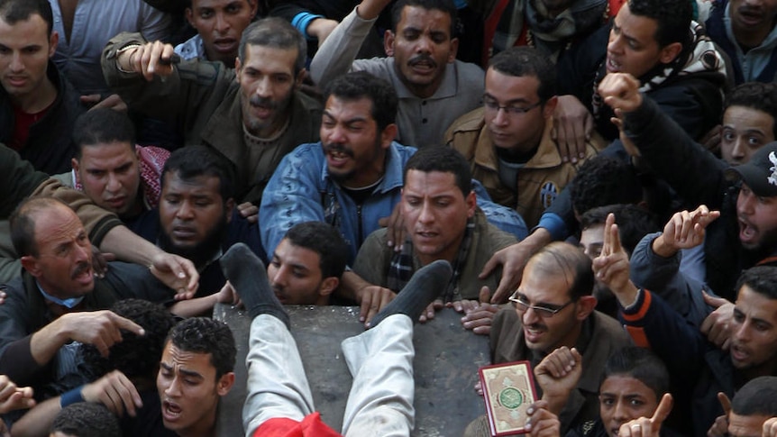 Egyptian demonstrators carry the body of a dead comrade wrapped in the Egyptian flag