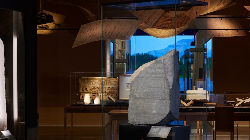 The rosetta stone in a glass display cabinet in a room at the mueseum. 