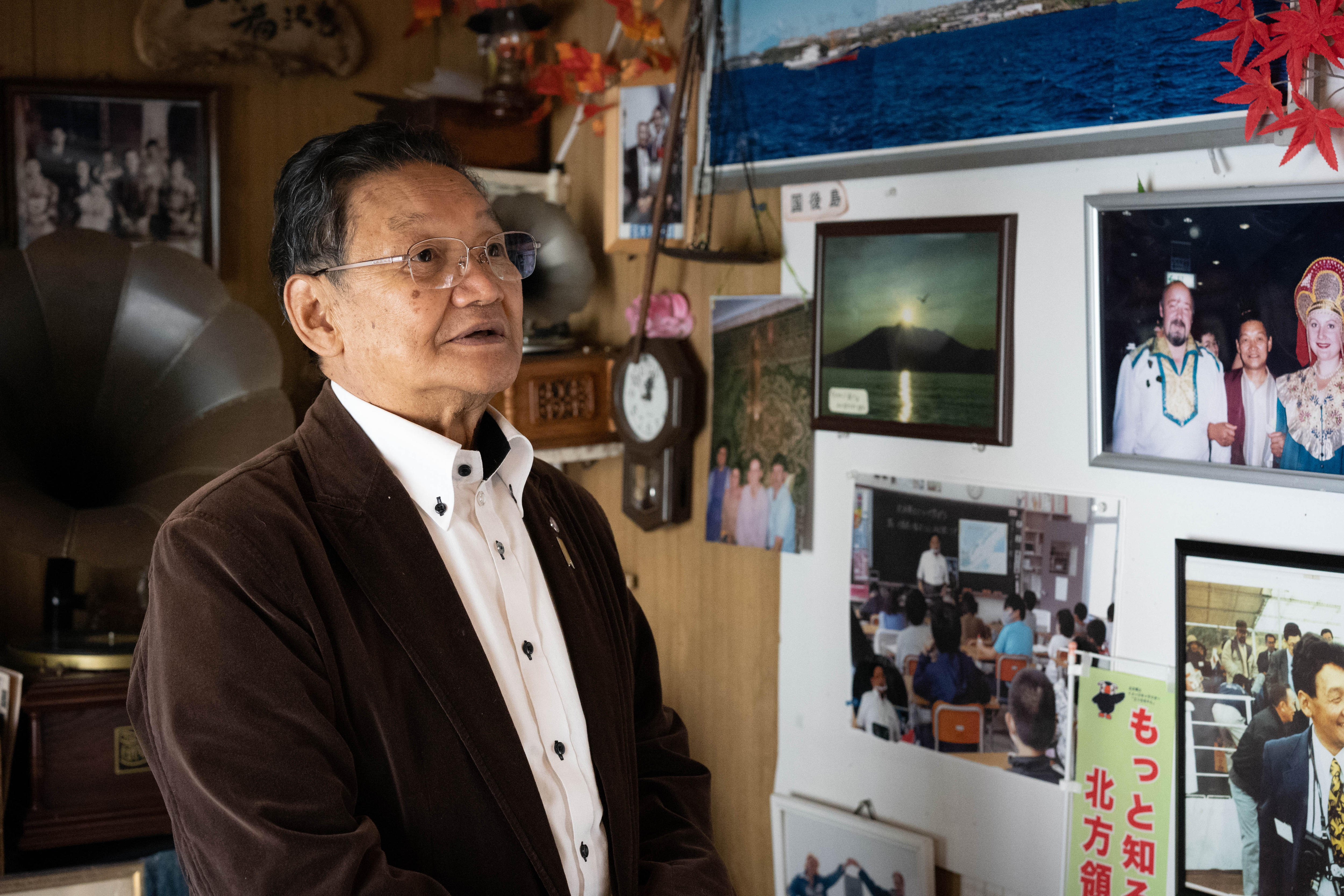 An older Japanese man looks at a wall covered in photos 