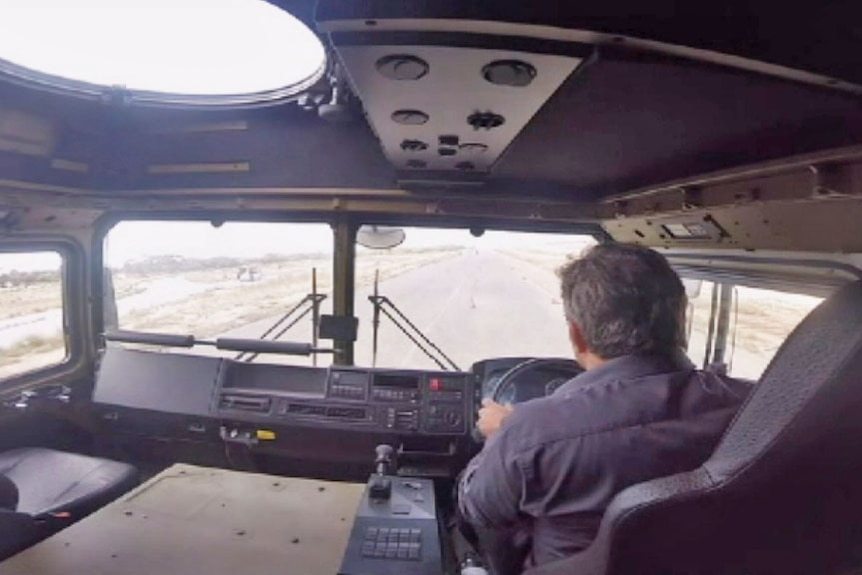 Interior view of a military truck being driven by a man.