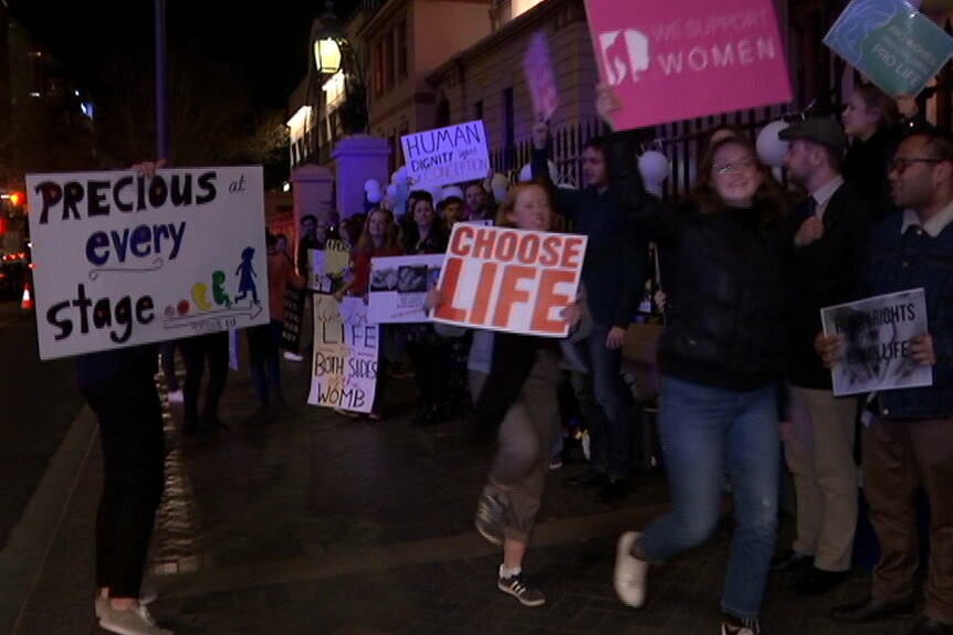 Pro-life protesters hold up signs outside Parliament