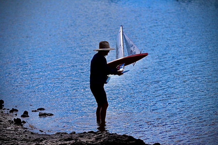 Man holding radio controlled model yachts racing in Manly Harbour