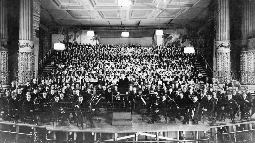 Black and white image of a large orchestra and choir on stage