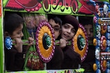 Pakistani children travel to school in a van in Peshawar